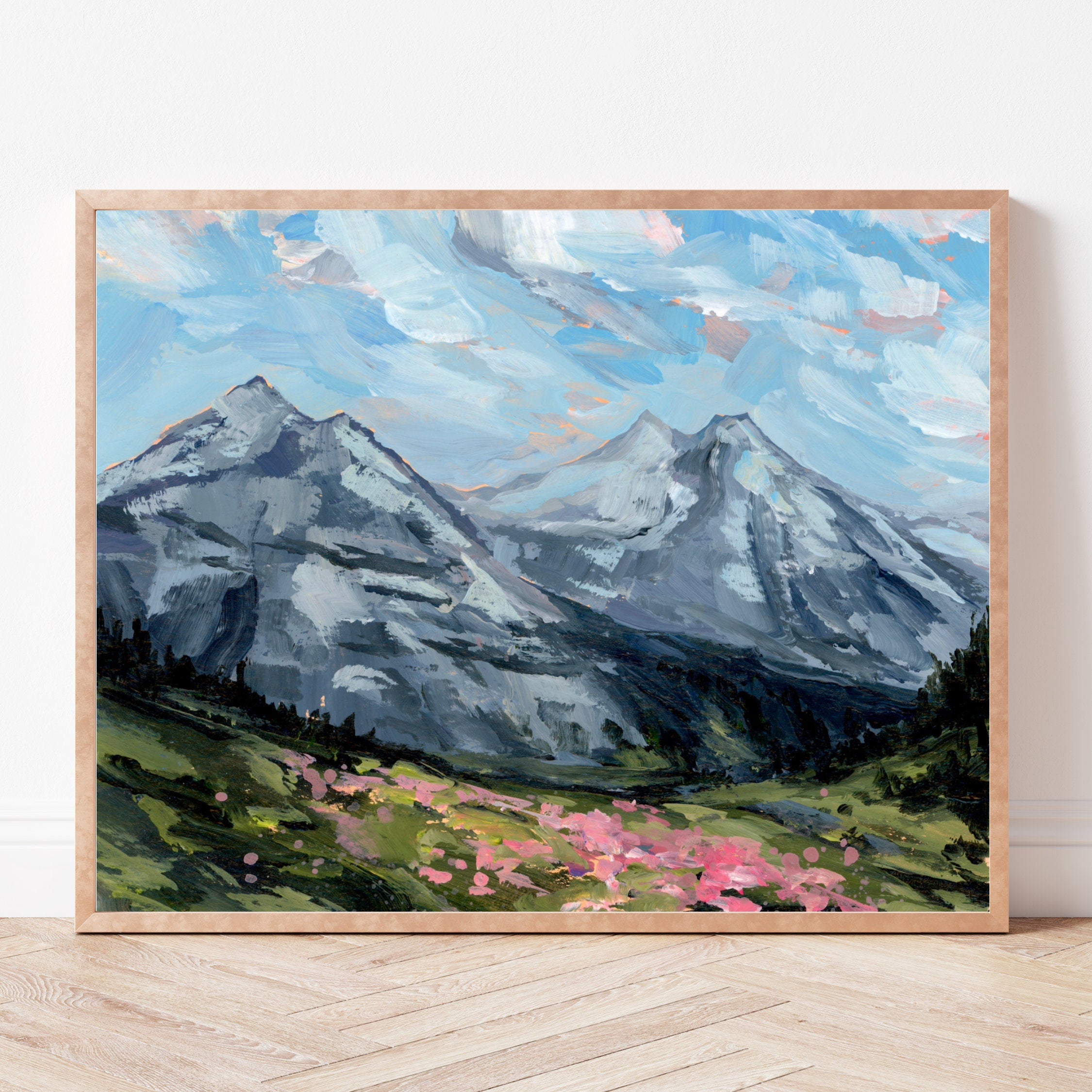 Framed painting of mountains and pink flowers on a white wall.