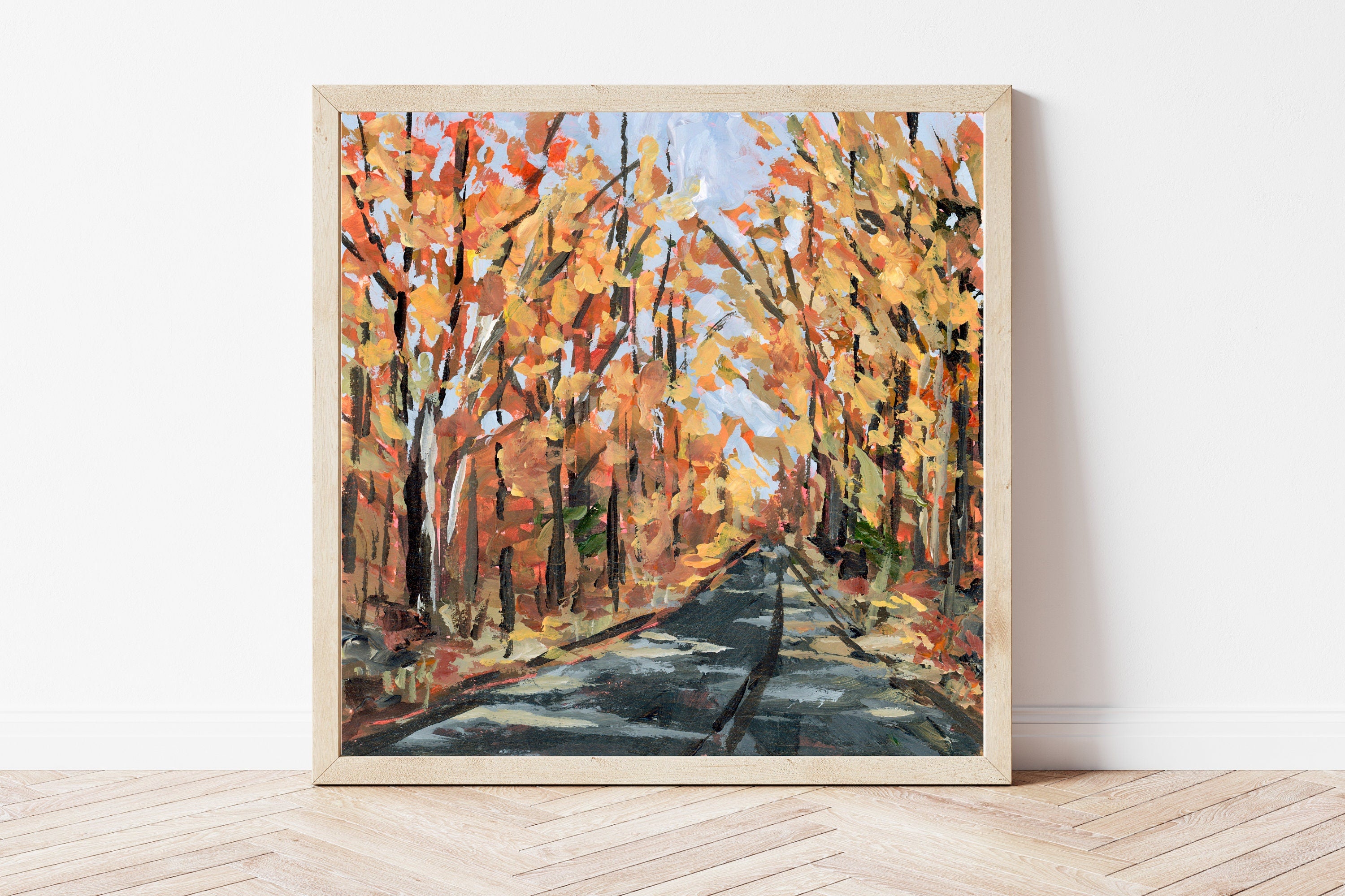 Framed painting of a autumnal forest scene on a white wall.
