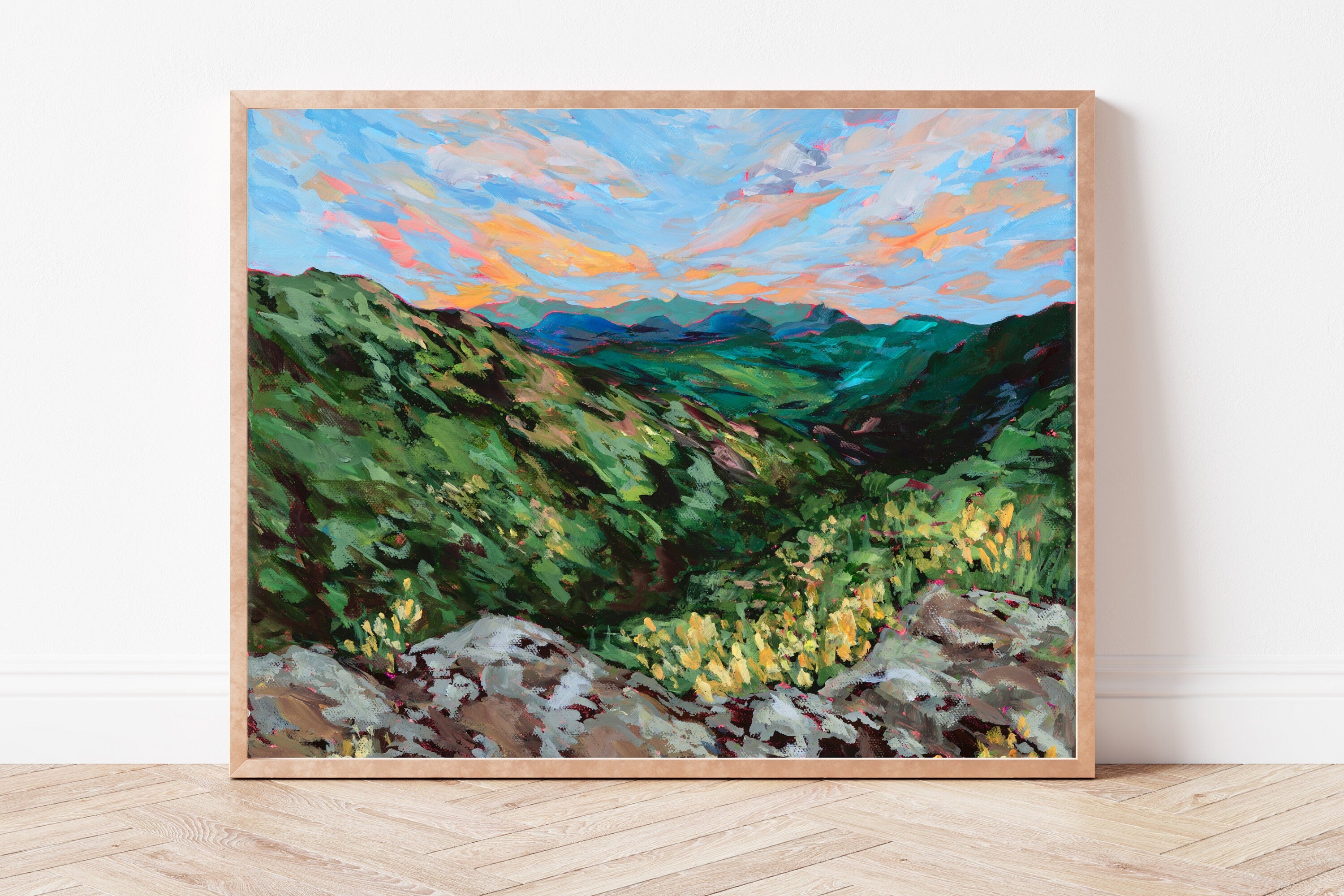 Framed painting of a mountain landscape with green hills and blue sky.