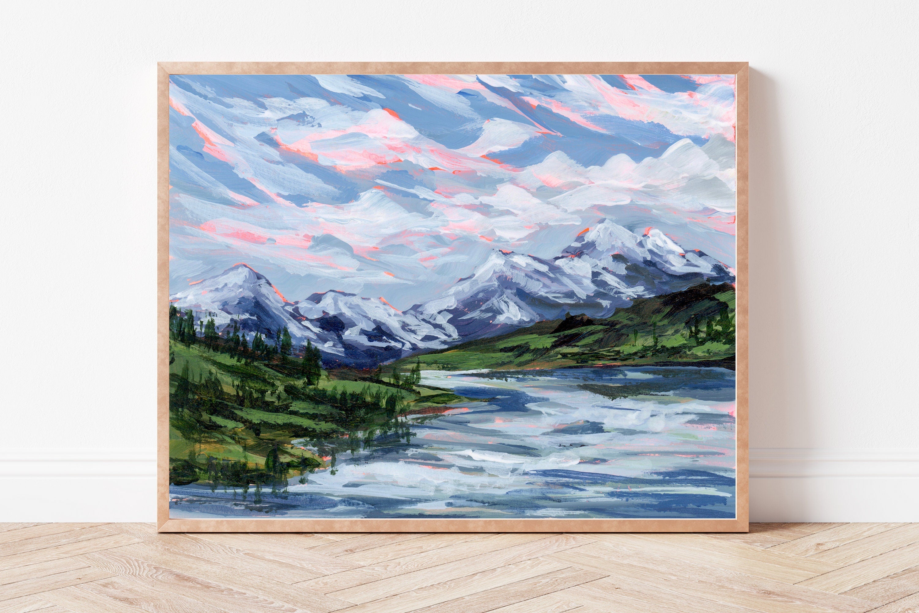 Framed print of a mountain landscape with a lake on a white wall.