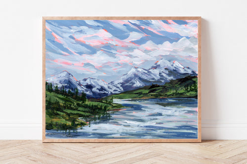 Framed print of a mountain landscape with a lake on a white wall.