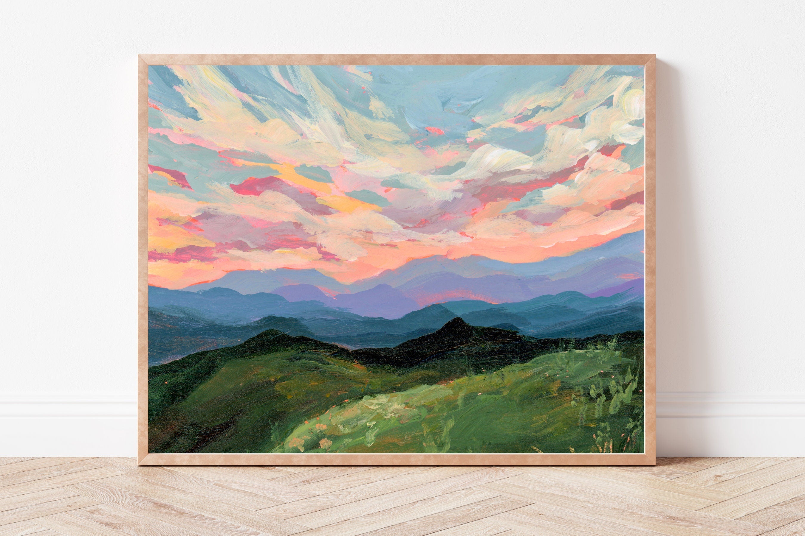 Framed fine art print of a colorful sky over green hills facing the Blue Ridge Mountains on a white wall.