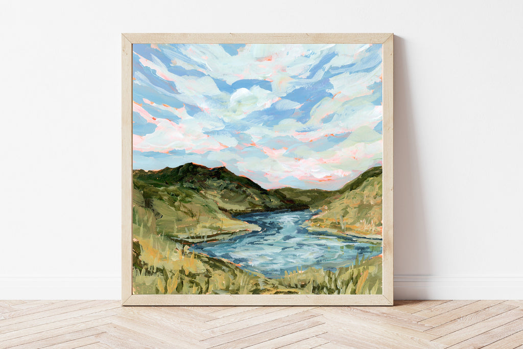 Framed painting of a Missouri landscape with a river and rolling green hills on a white wall.