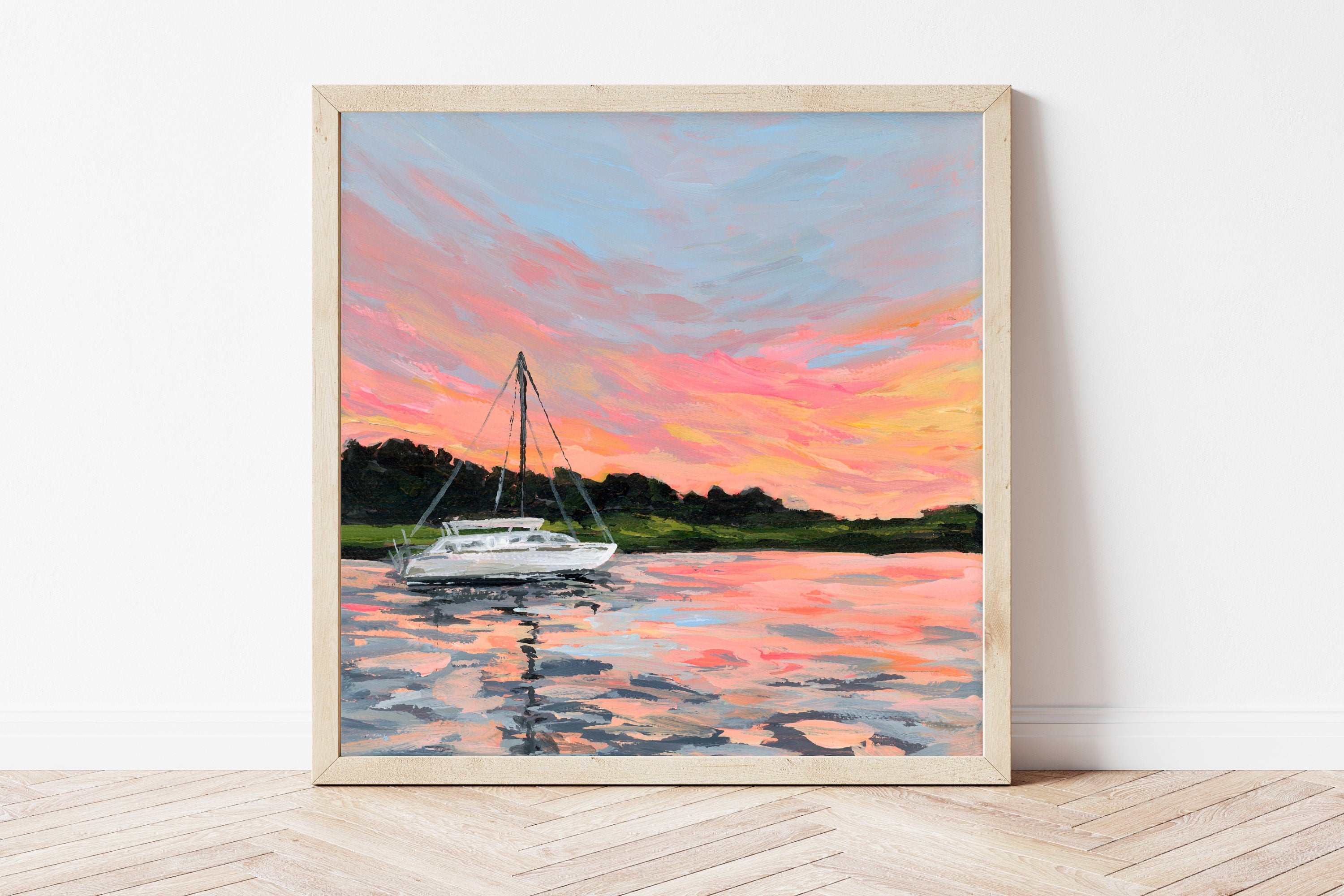 Framed painting of a sailboat on water with a colorful sunset sky.
