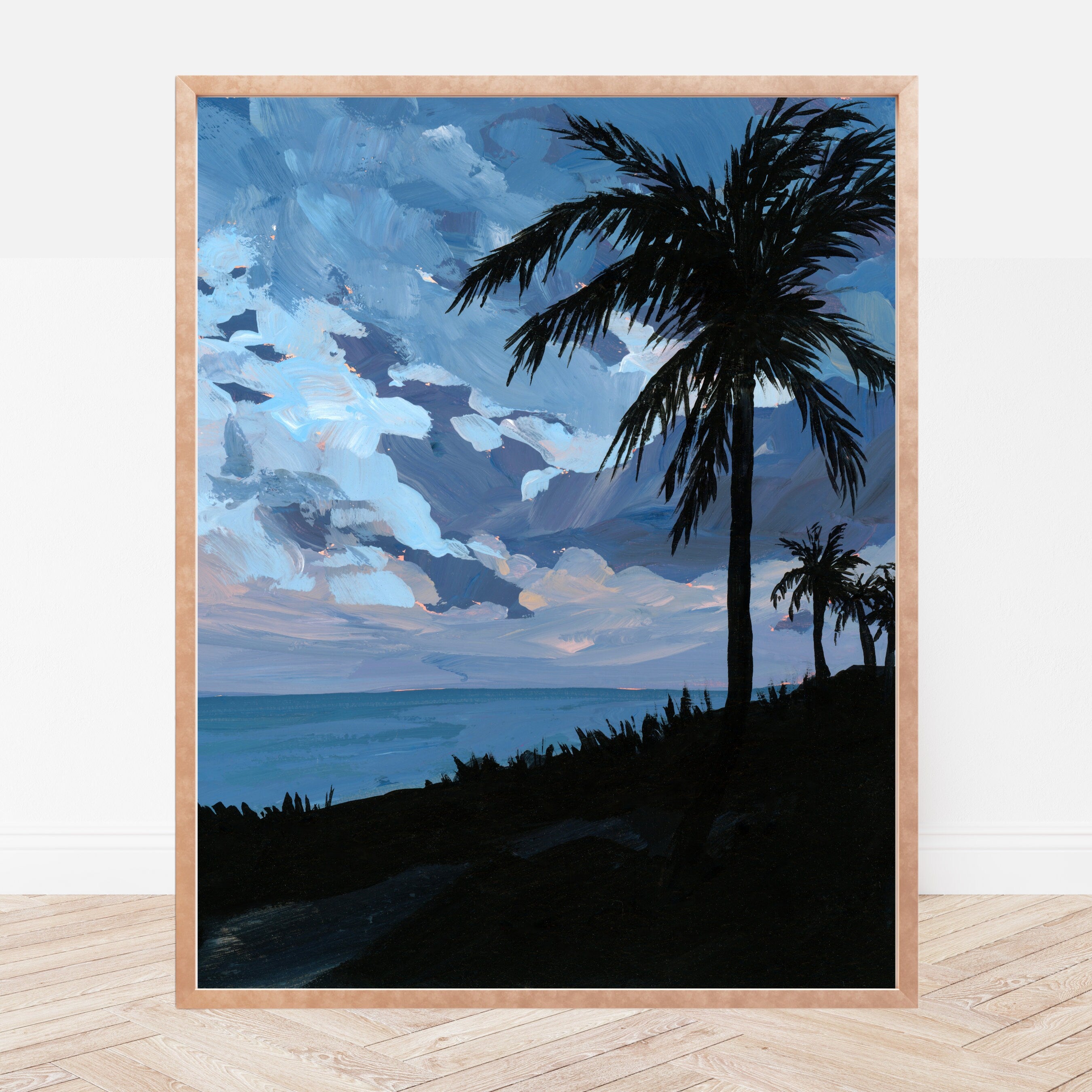 Framed artwork of a beach scene at dusk with palm tree silhouettes against a blue sky.