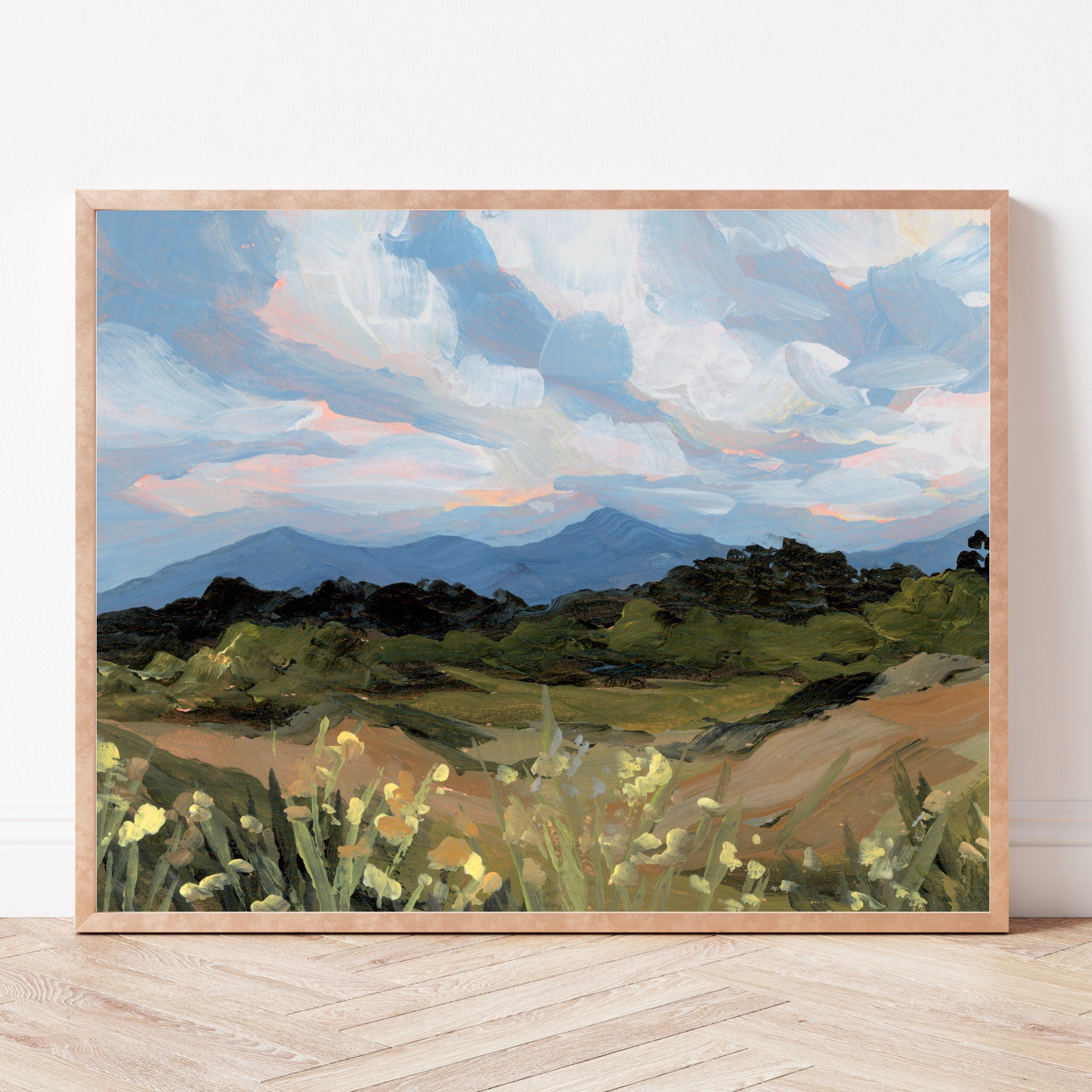 Framed painting of a Colorado Springs landscape with mountains and fields on a white wall.