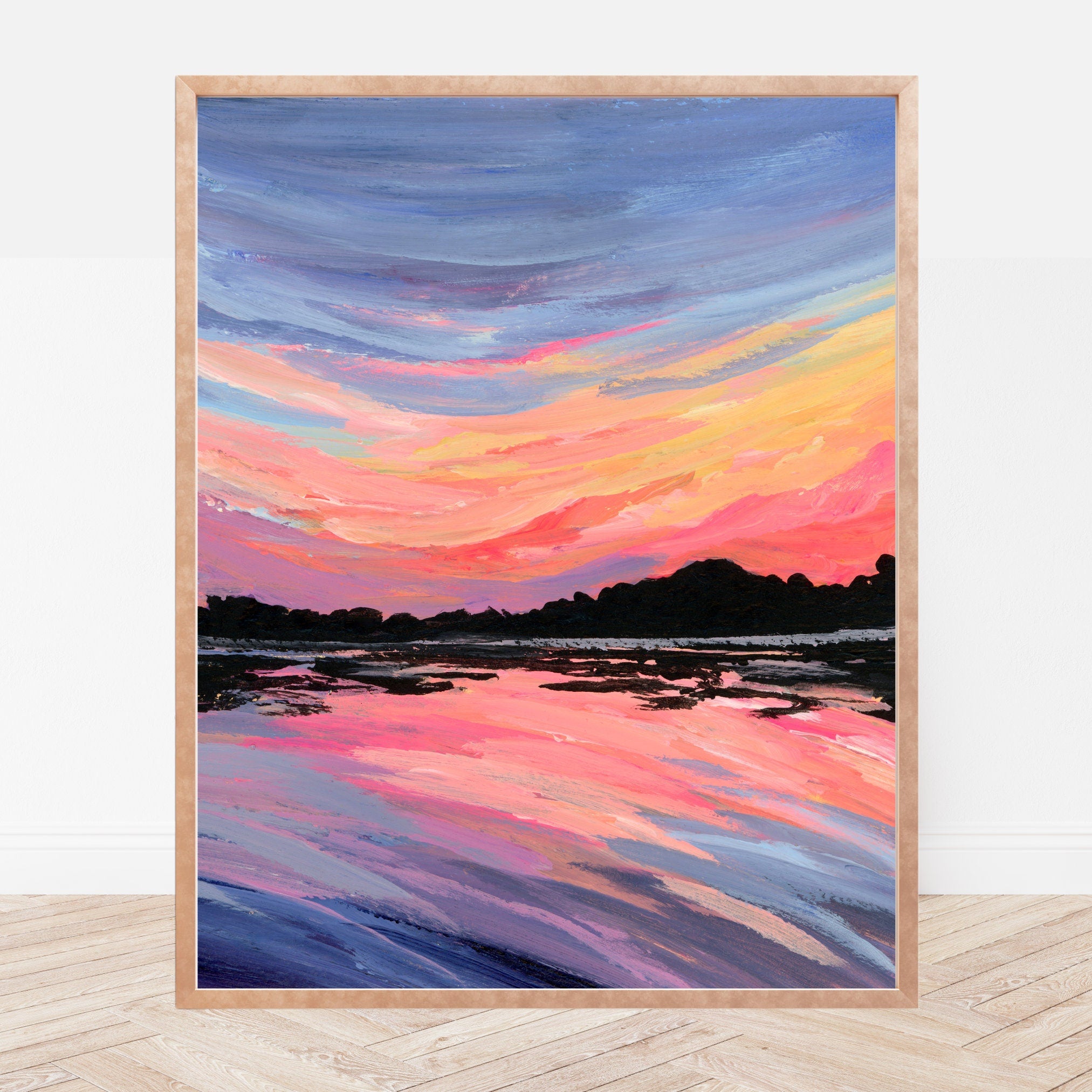 Framed artwork of a colorful rainbow sunset over water on a white wall.
