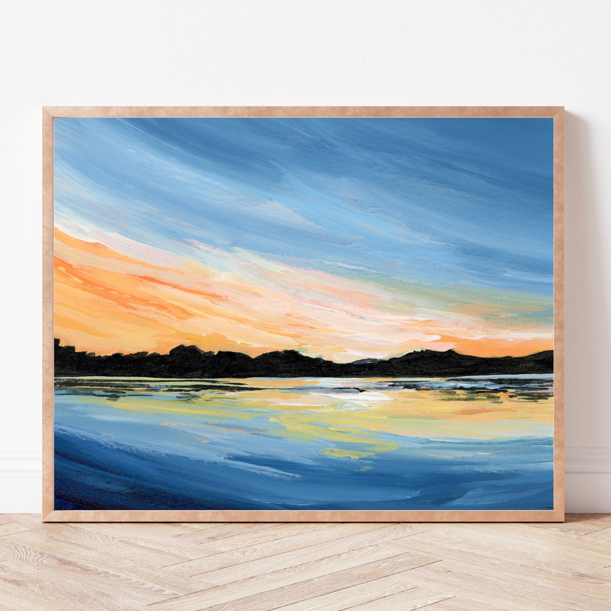 Framed print of a landscape painting featuring a sunset over water with a wooden frame.