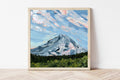 Framed landscape artwork featuring Oregon's Mount Hood underneath a blue sky with bright white clouds. 