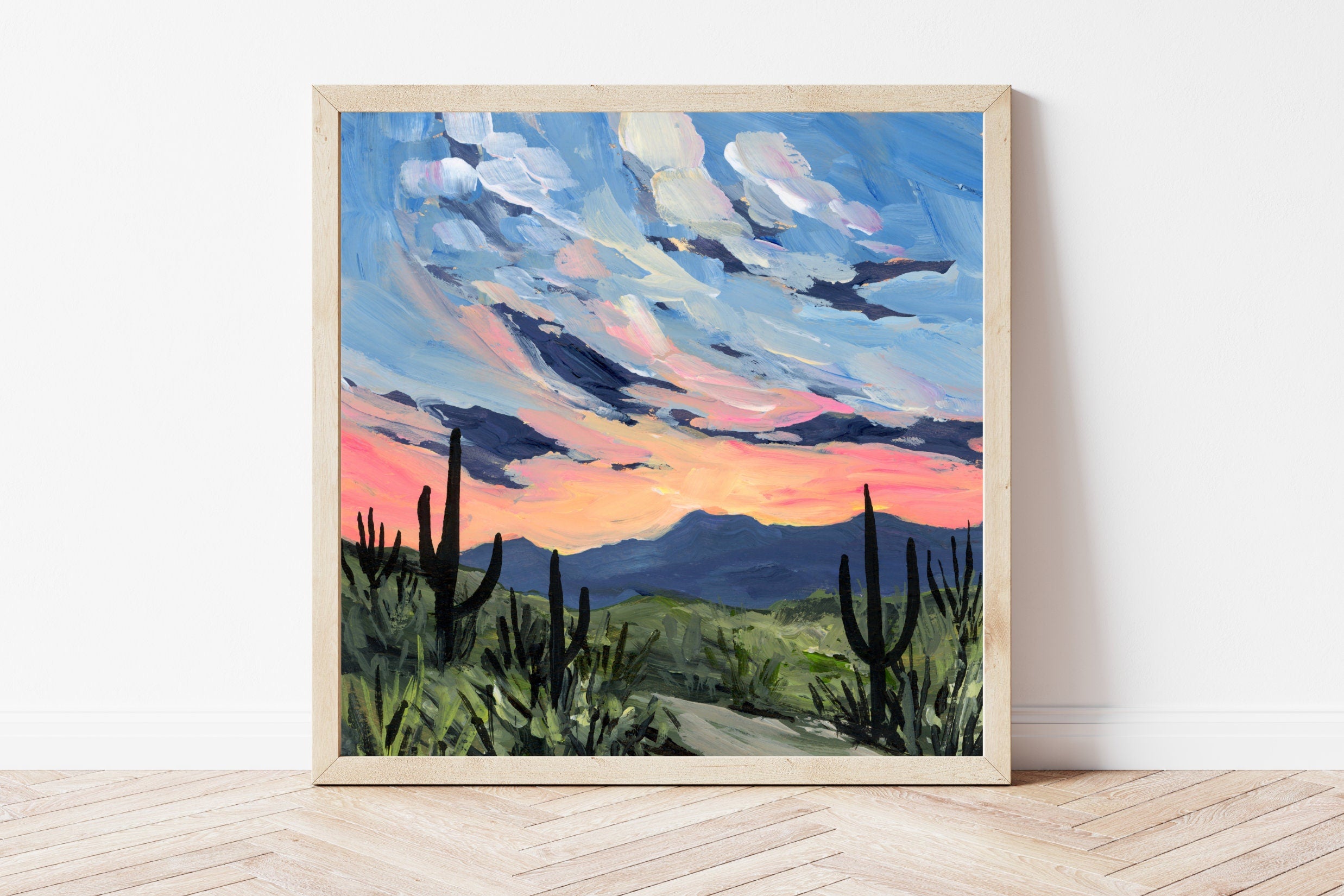Framed painting of a desert landscape with a colorful sky.