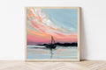 Framed artwork of a sailboat on water with a colorful sky.