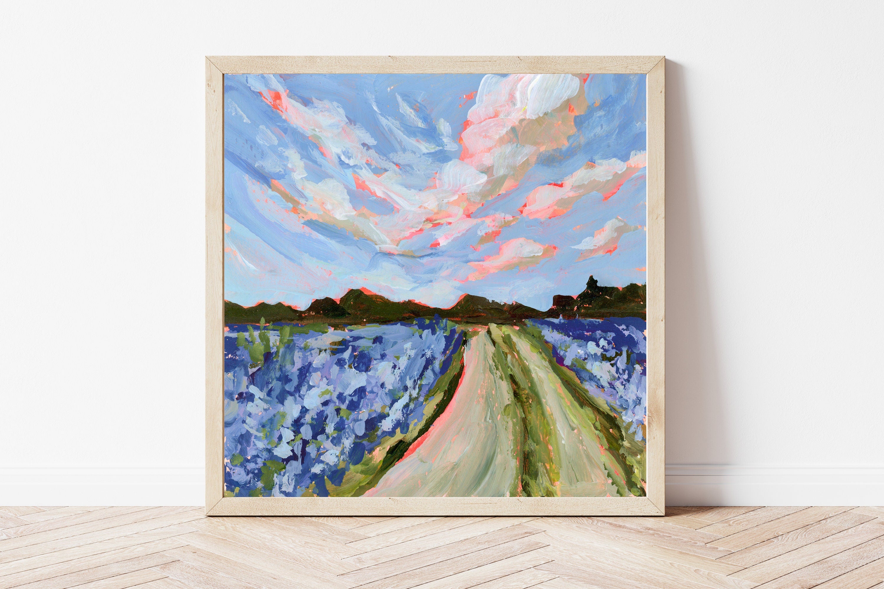 Framed painting of a hill country landscape with bluebonnet flowers and a blue sky.