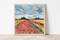 Framed painting of a tulip field with a blue sky and clouds.