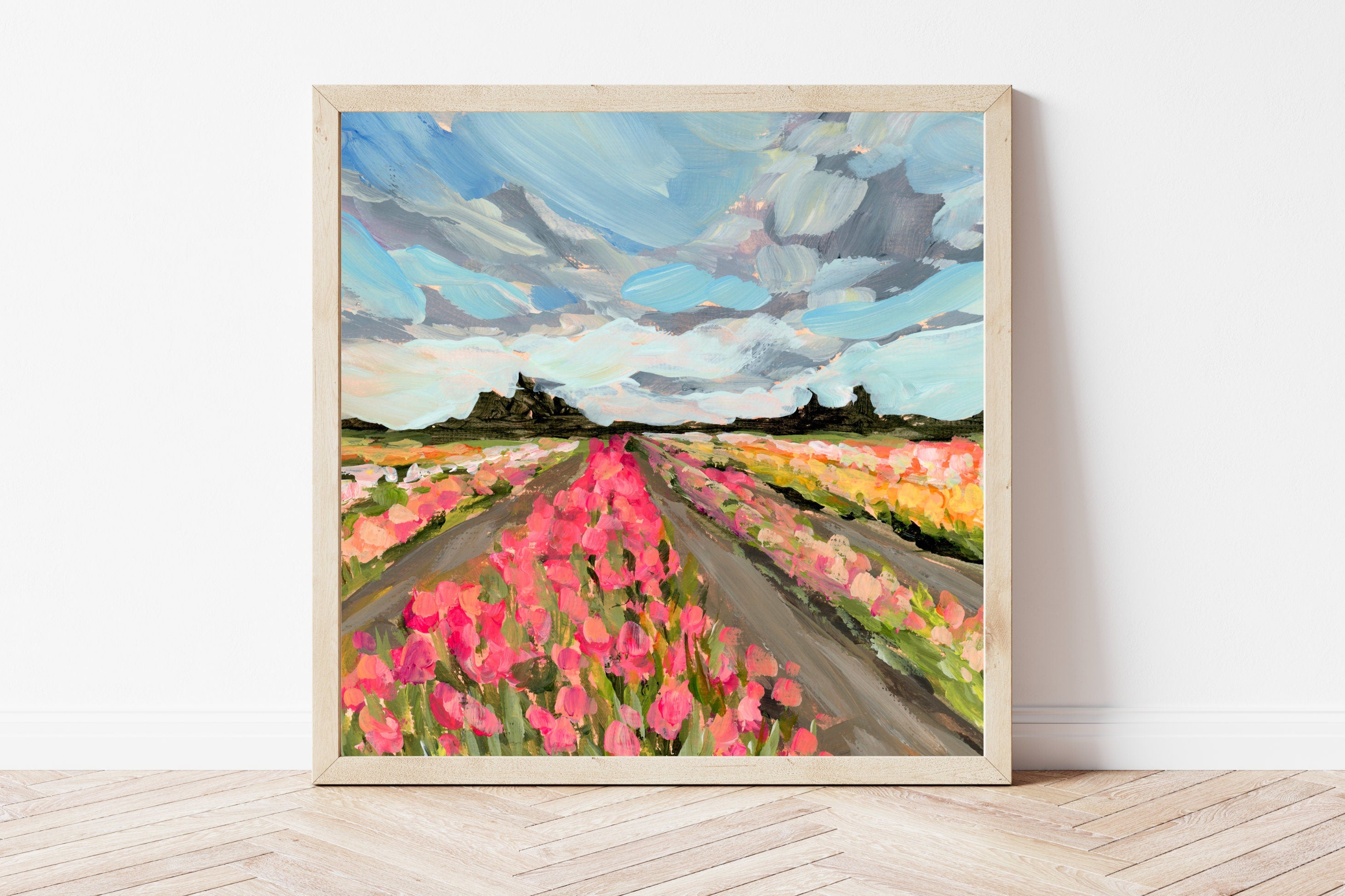 Framed painting of a tulip field with a blue sky and clouds.