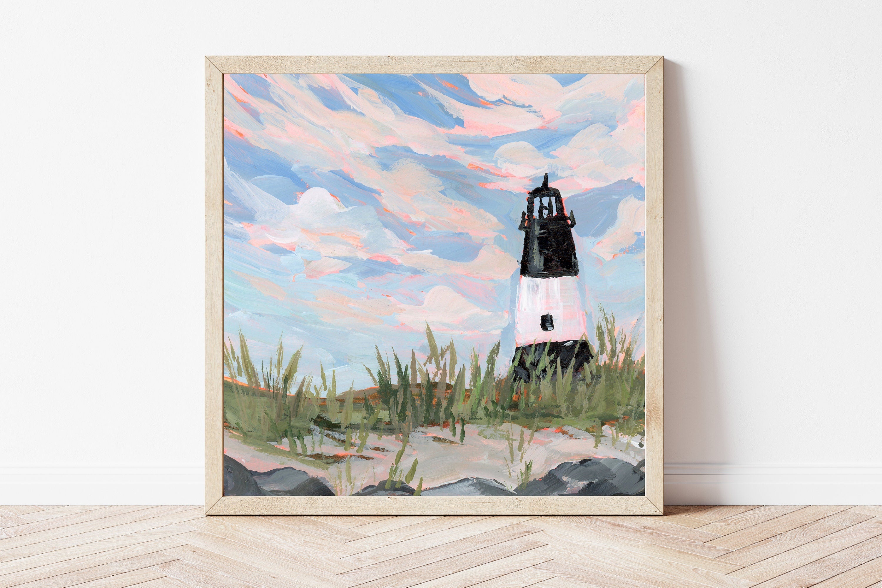 Framed artwork of a black and white striped lighthouse surrounded by beach grass against a blue sky.