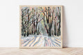 Framed painting of a winter forest scene with bold, defined brushstrokes on a white wall.