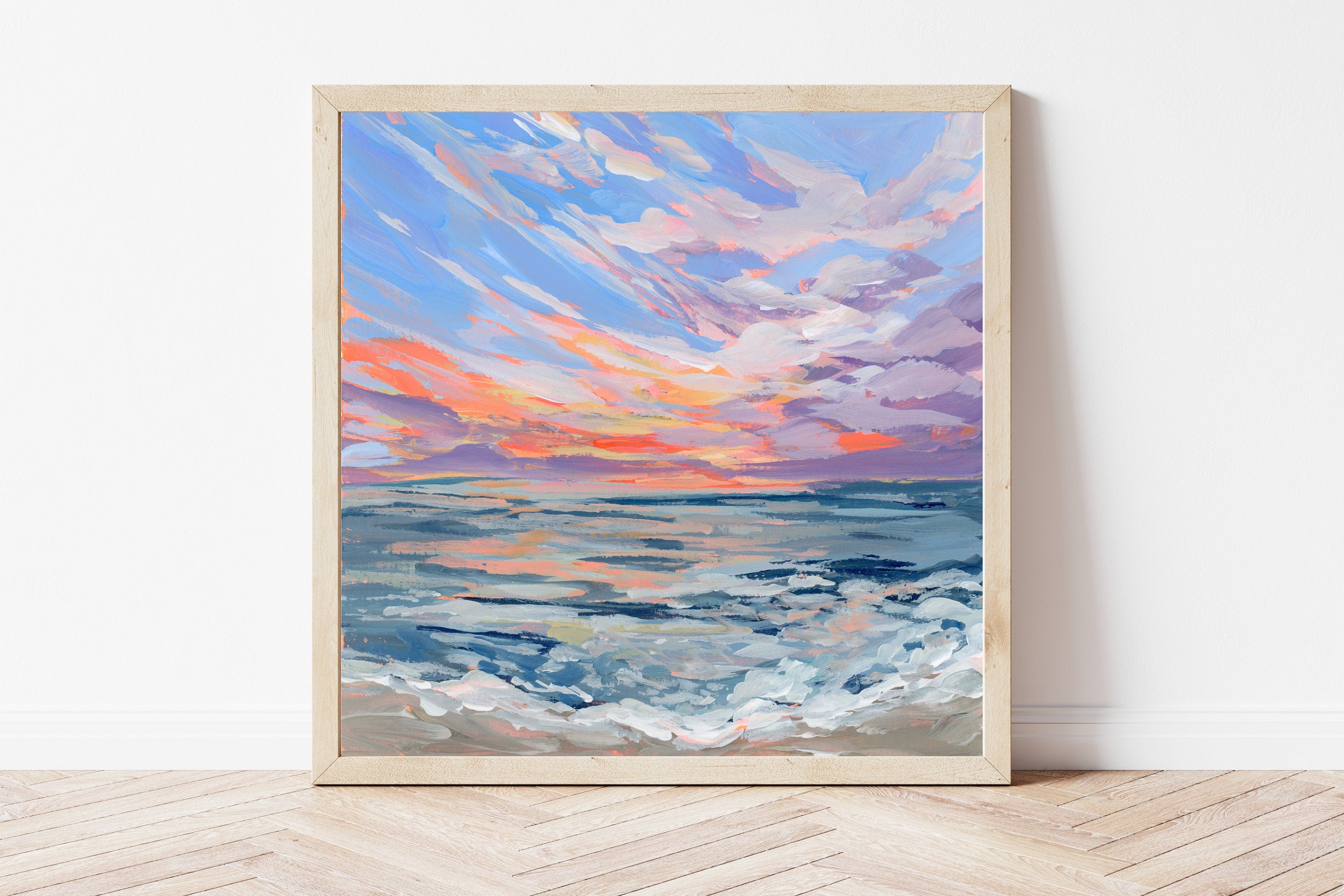 Framed artwork of a sunset over water at Virginia Beach on a white wall.