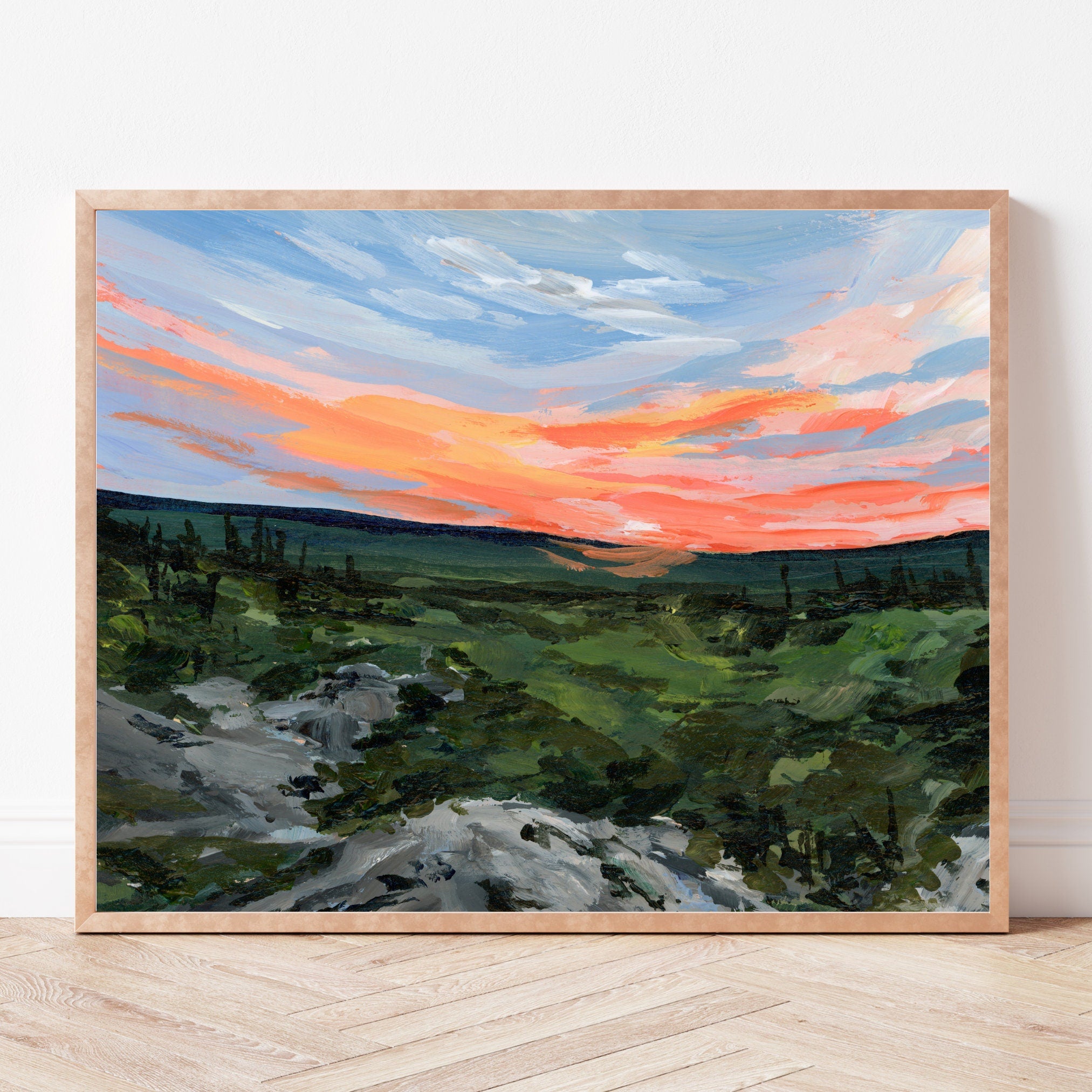 Framed painting of an orange sunset over a West Virginia landscape with trees and rocks.