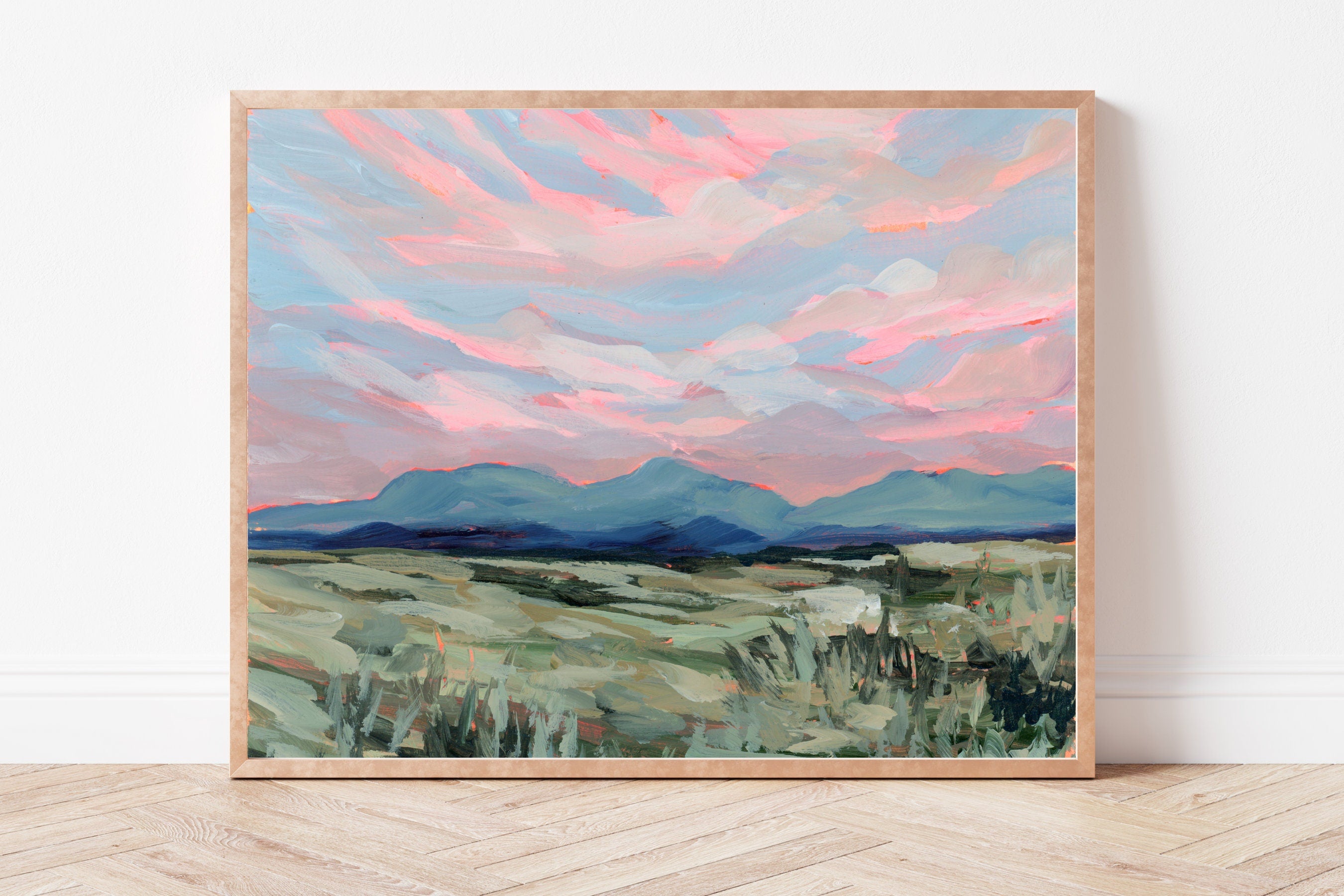 Framed painting of a rural, Wyoming landscape with pink and blue sky on a white wall.