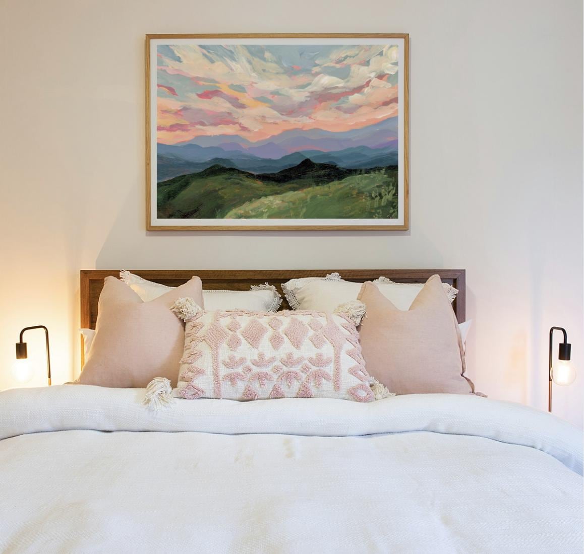 Bedroom with a bed featuring pink decorative pillows and a framed Blue Ridge Mountains landscape painting on the wall.