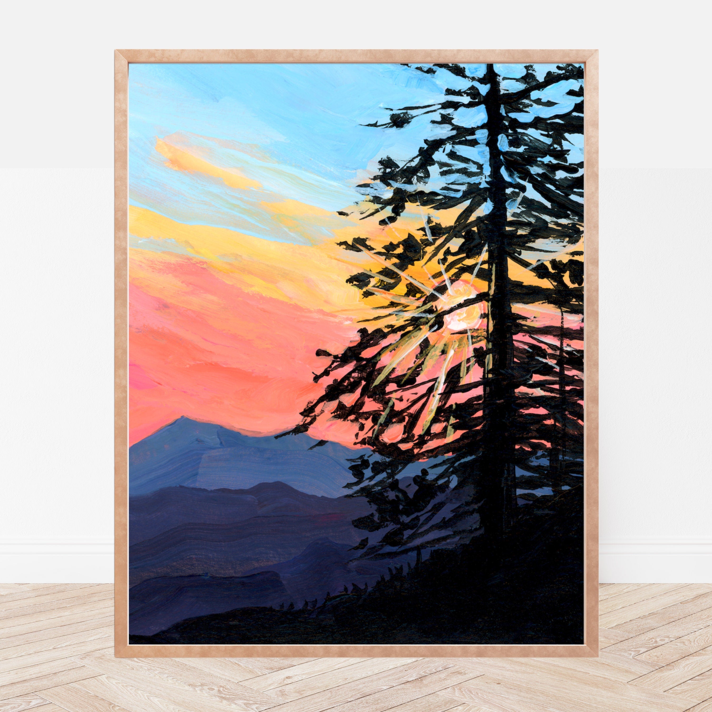 Framed artwork of a sunset with trees and mountains